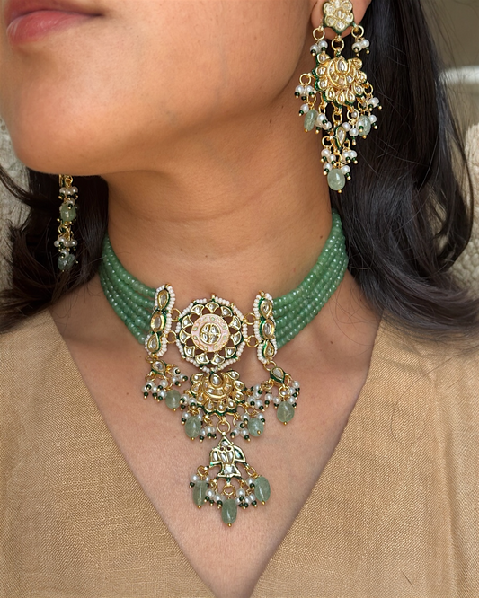 Close-up of a person wearing a green beaded necklace and matching earrings.
